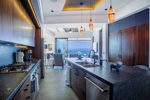 A modern kitchen with a central island, stainless steel appliances, and pendant lighting.