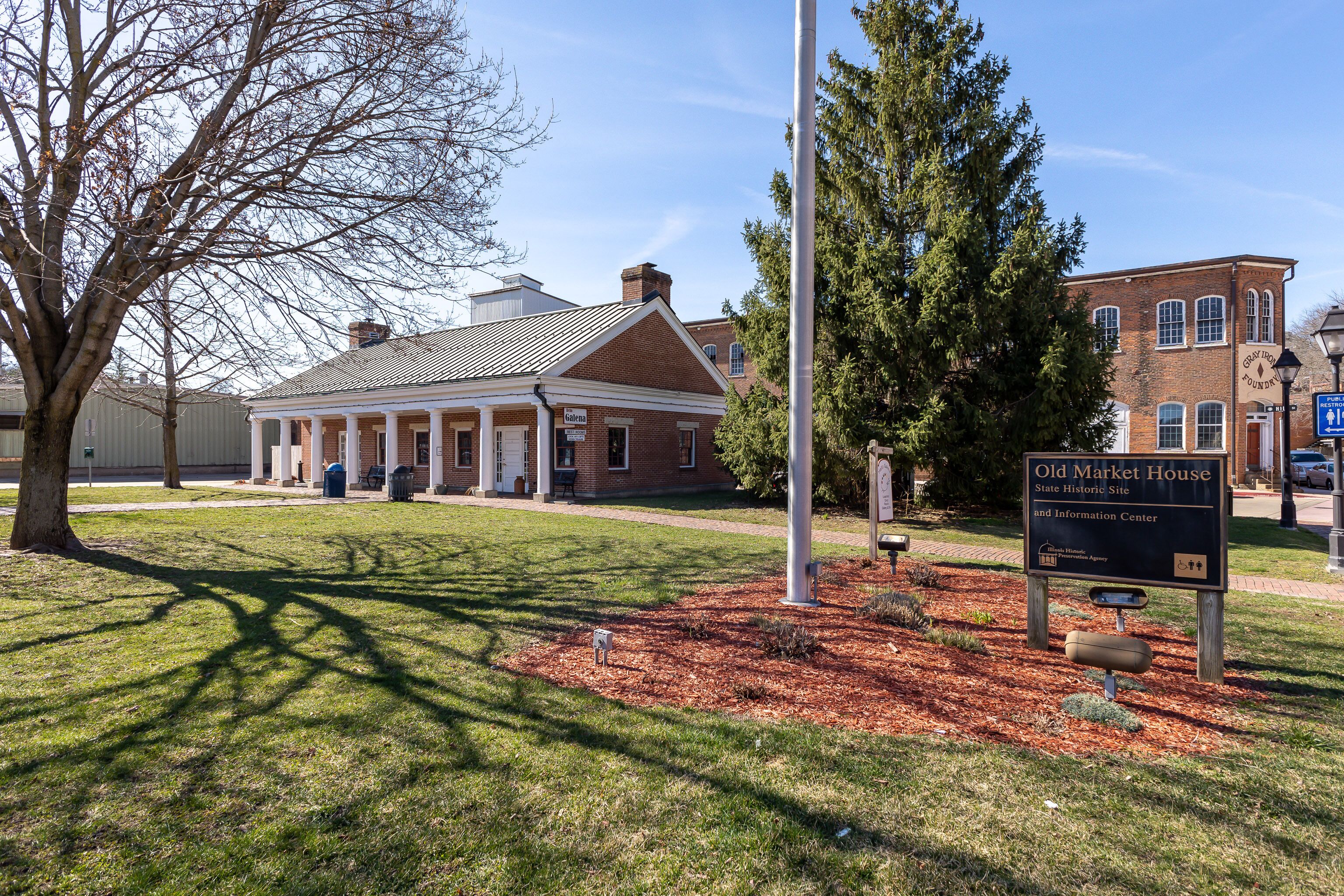A historic building with a brick facade, a covered porch, and a sign indicating it is a state historic site and information center.