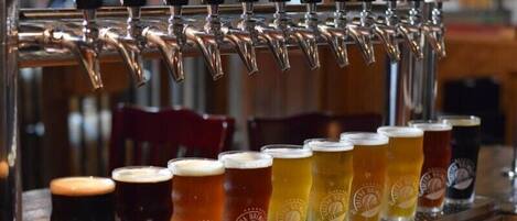 Un bar con varias griferías de cerveza y una variedad de vasos llenos de diferentes tipos de cerveza.
