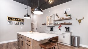 Una cocina moderna con una isla central, iluminación colgante y un adorno de cabeza de toro.