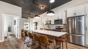 Una cocina moderna con una isla central, electrodomésticos de acero inoxidable y taburetes de bar.