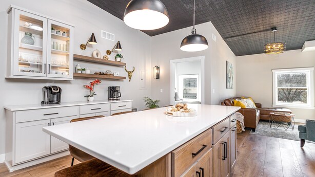 Una cocina moderna con armarios blancos, una isla grande e iluminación colgante.