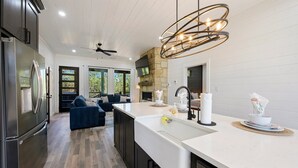 A modern kitchen with a large island, stainless steel appliances, and a stone accent wall. - 54BD/3BTH Serenity Skyline Sleeps 14, Hot Tub and more! (Broken Bow)
