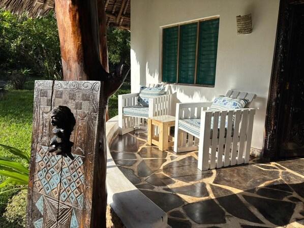 A patio with a stone floor, white furniture, and a decorative wooden panel.