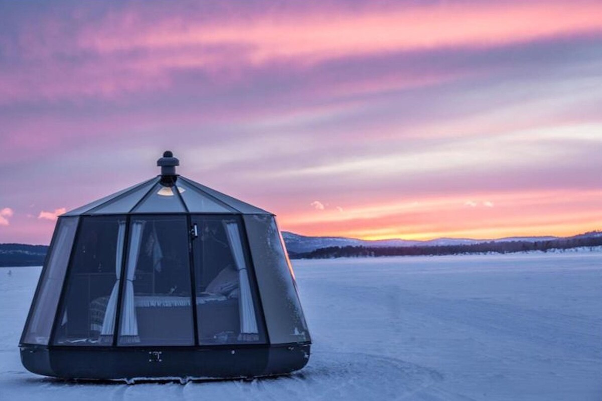 A geodesic dome structure on a frozen landscape with a sunset in the background.