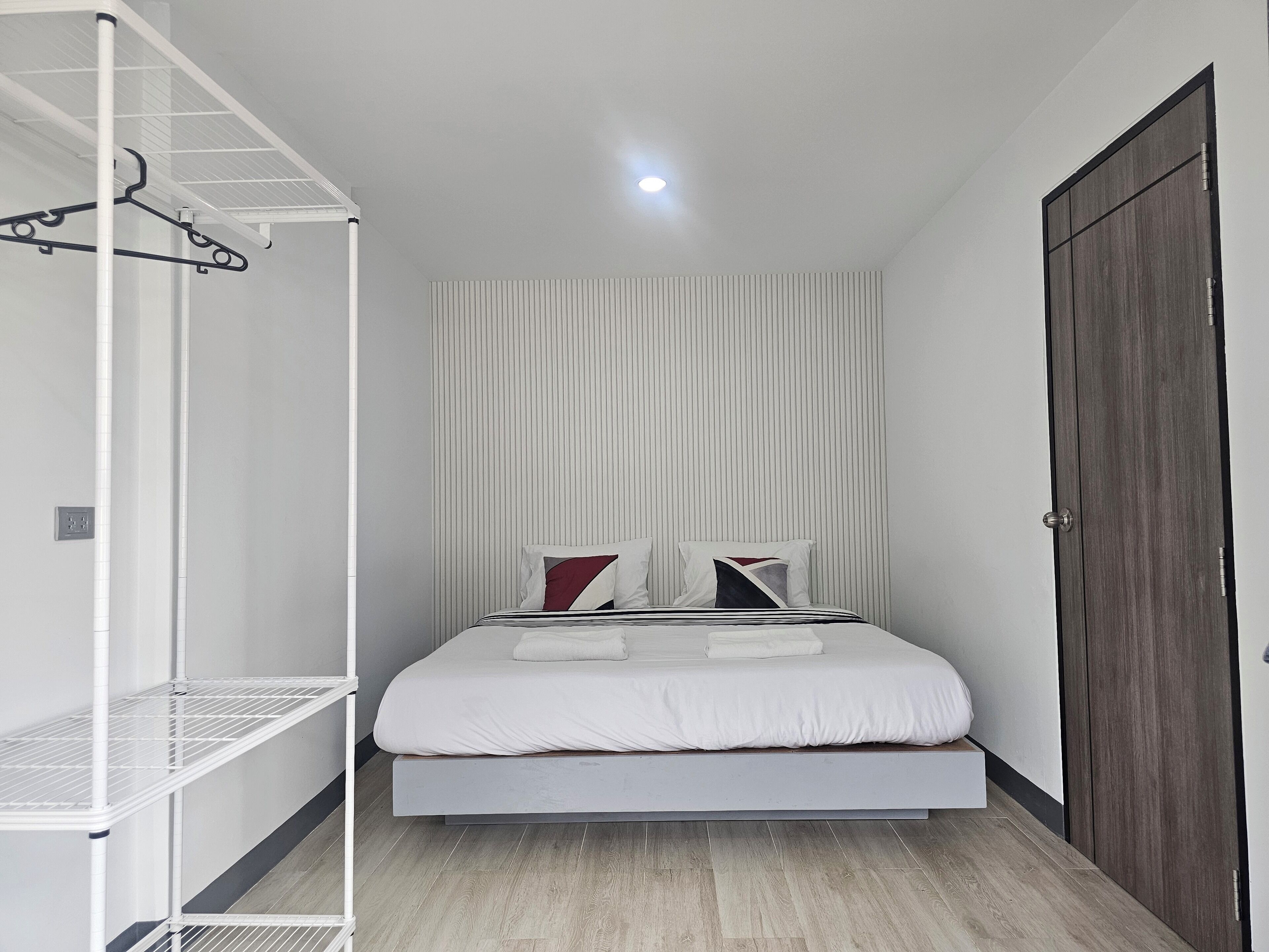 Une chambre à coucher moderne avec un lit, une étagère blanche et une armoire en bois.