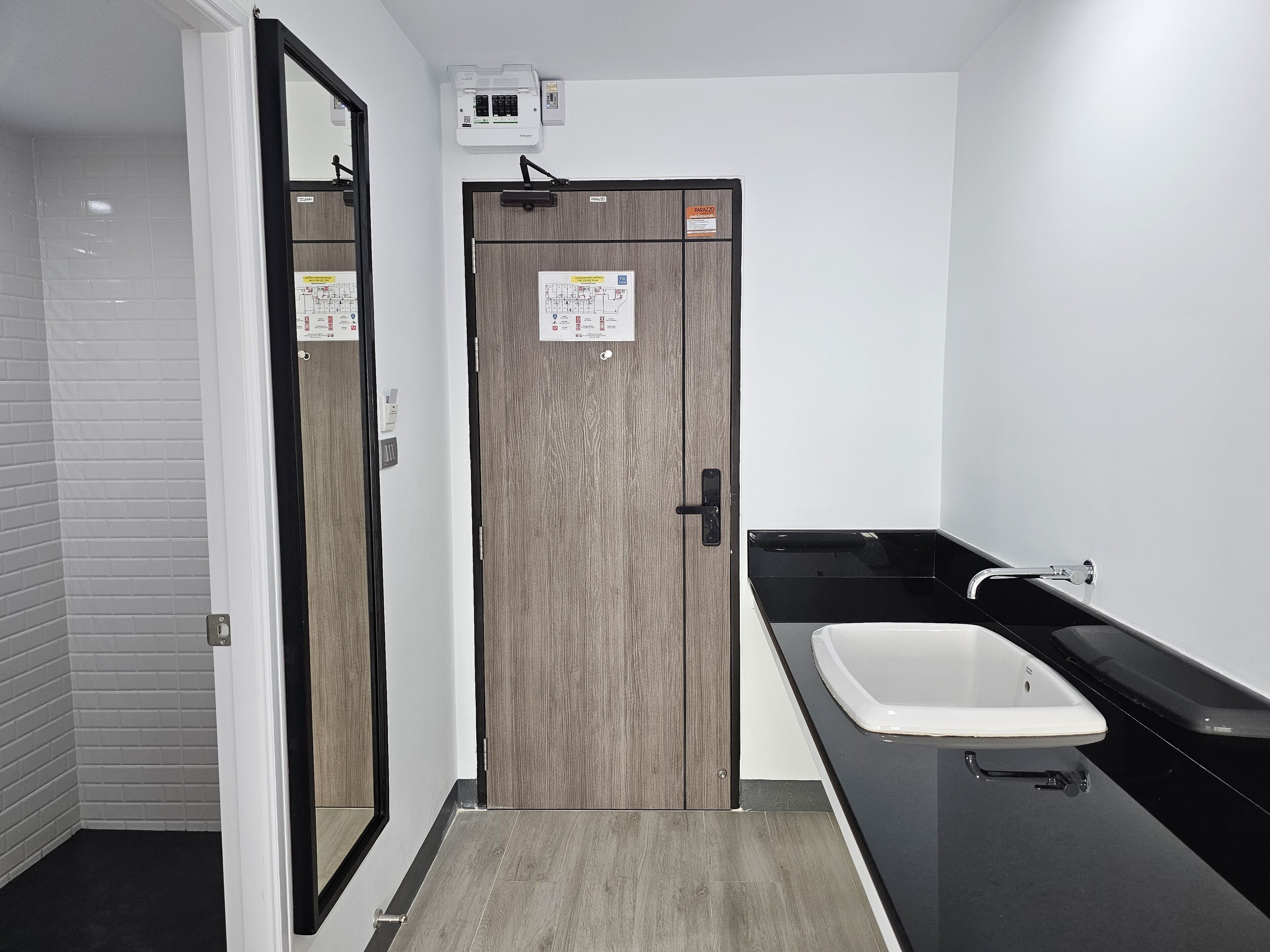 A small bathroom with a wooden door, a white sink, and a mirror.