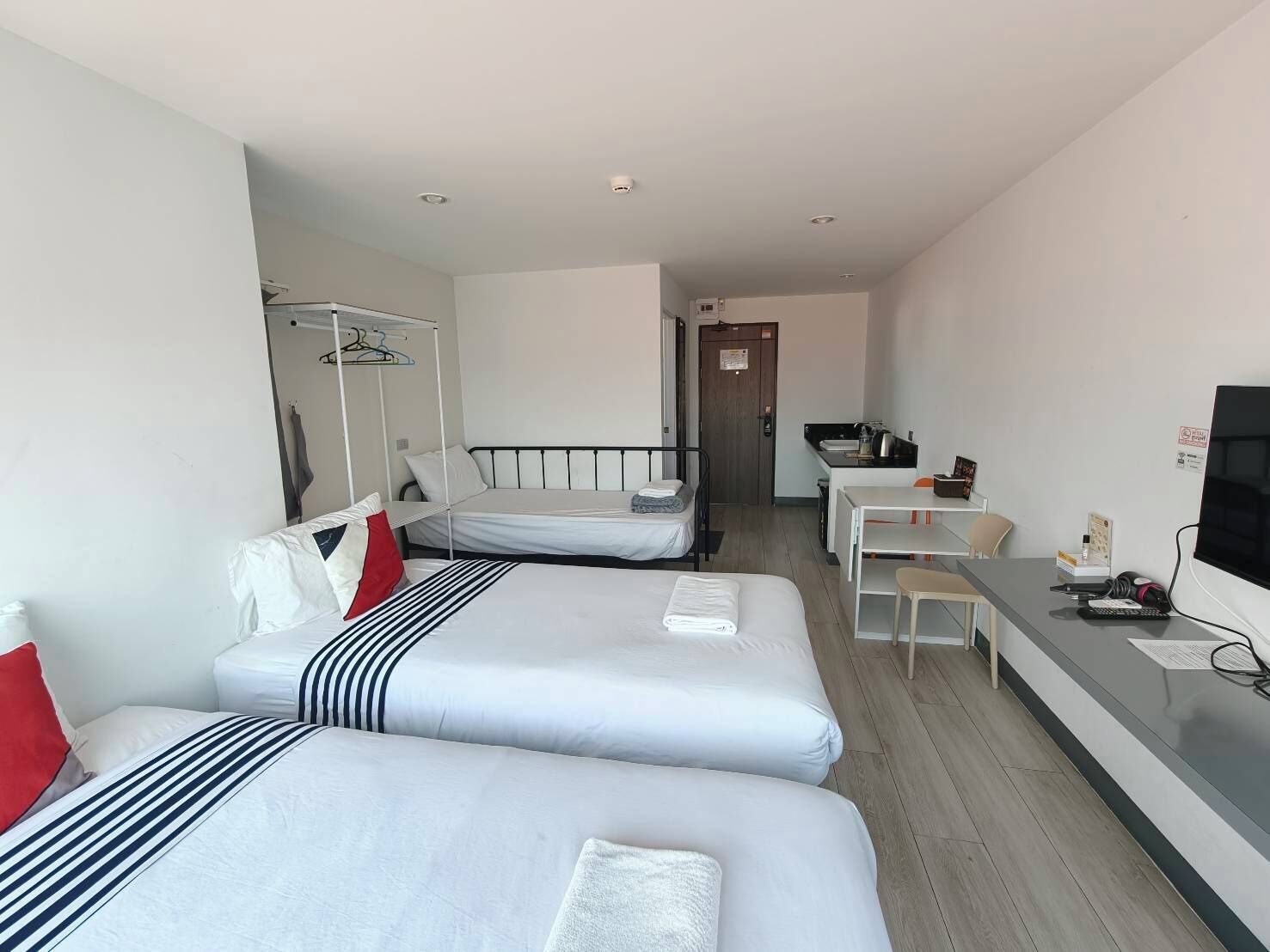 Una habitación de hotel con dos camas, un escritorio, una silla, un televisor y un armario.