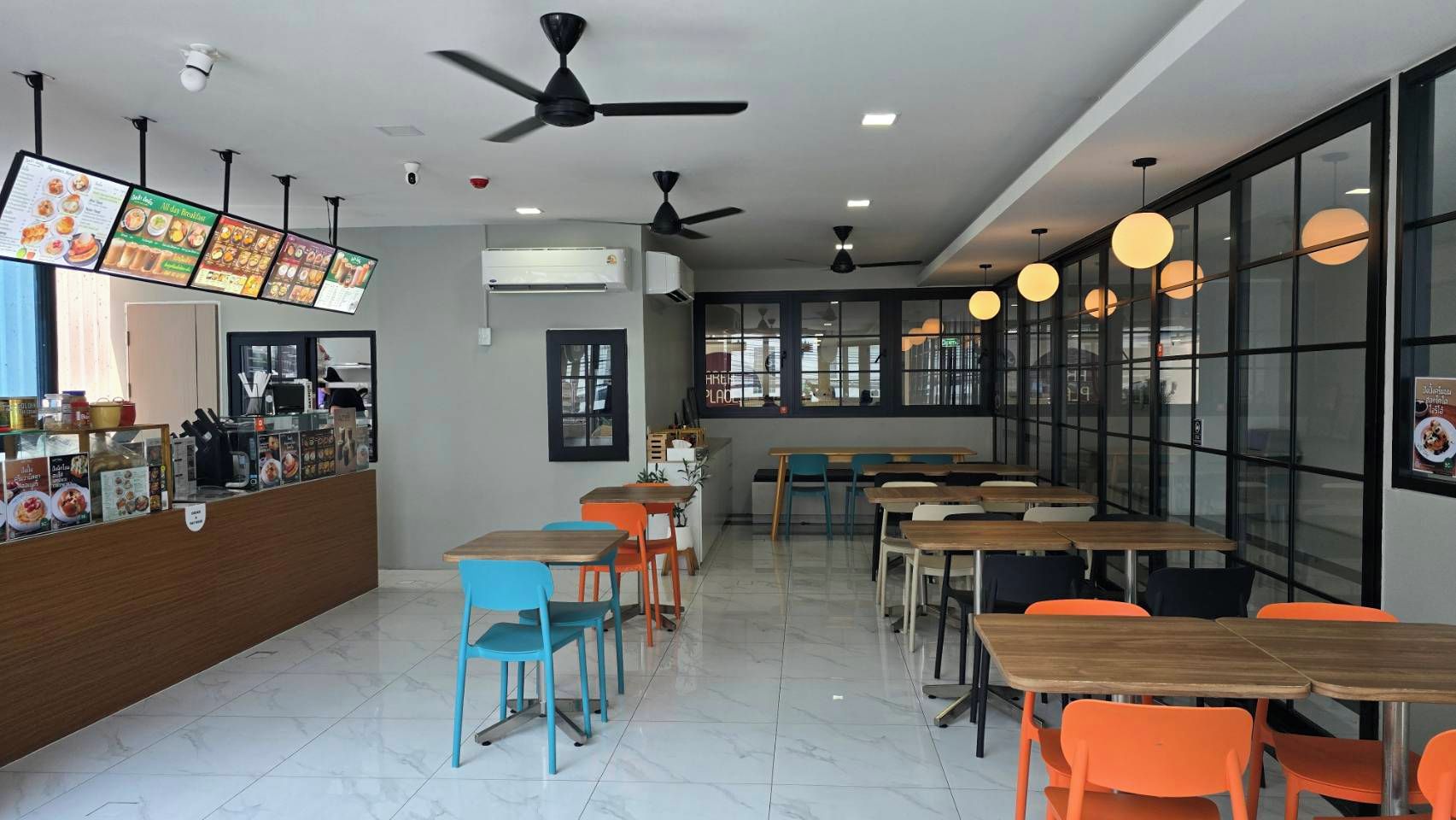 A restaurant with multiple tables and chairs, a counter with a menu, and ceiling fans.