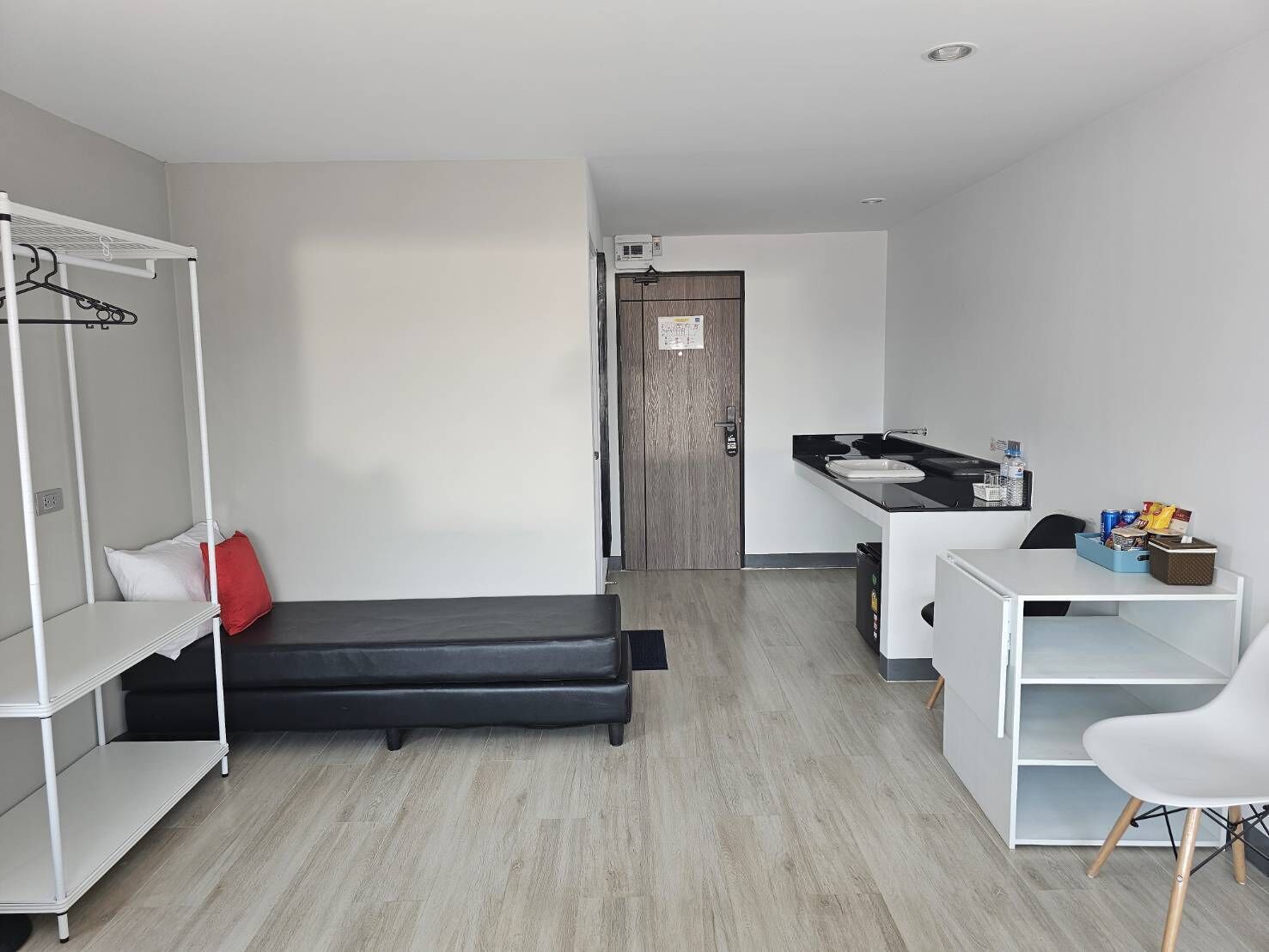 Ein kompakter, moderner Raum mit Bett, Schreibtisch und Kleiderschrank.