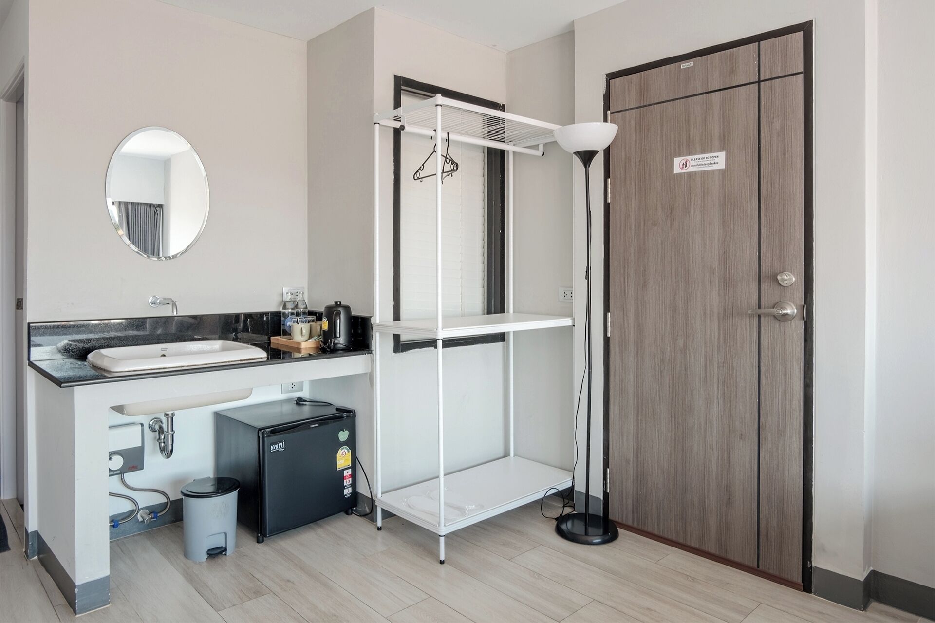 A bathroom with a sink, mirror, toilet, and a compact storage unit.
