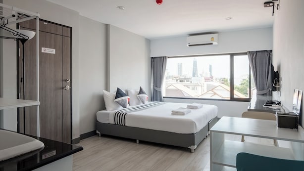 A modern hotel room with a bed, a desk, and a view of the city skyline. - Area Place Hotel (Bangkok)