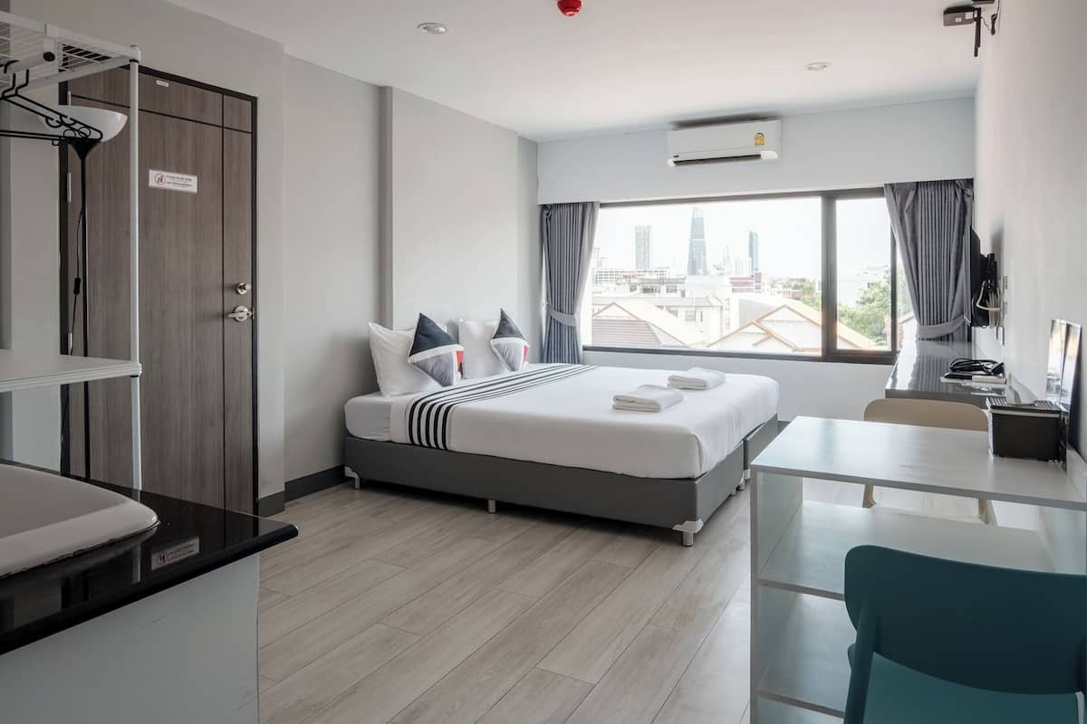 A modern hotel room with a bed, a desk, and a view of the city skyline.
