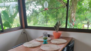 A wooden dining table with woven placemats, a vase with green plants, and a potted cactus. - Tu Mejor Opción de Hospedaje en Laguna Hule (Río Cuarto)