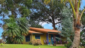 A yellow house with a red roof, surrounded by lush greenery and trees. - Tu Mejor Opción de Hospedaje en Laguna Hule (Río Cuarto)