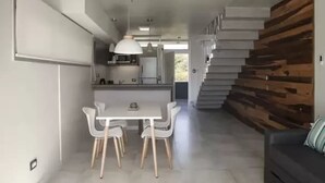 A modern kitchen with a central island, white chairs, and a dining table. - Nova Pampa apart&spa (Mar Azul)