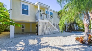 A two-story house with a covered porch and a staircase leading to the entrance. - Loggerhead Lagoon - Waterfront & Pet Friendly (Sugarloaf Key)