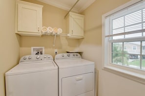 A laundry room with two stacked washers and dryers, a window with blinds, and a shelf with towels. - Loggerhead Lagoon - Waterfront & Pet Friendly (Sugarloaf Key)