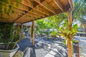 A covered outdoor area with a wooden structure, potted plants, and a gravel pathway.