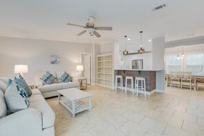 A modern living room with a sofa, coffee table, and a kitchen area with bar stools.