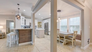 A spacious kitchen with a central island, white cabinetry, and a dining area with a table and chairs. - Loggerhead Lagoon - Waterfront & Pet Friendly (Sugarloaf Key)