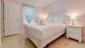 A bedroom with a bed, bedside lamps, a ceiling fan, and a door. - Loggerhead Lagoon - Waterfront & Pet Friendly (Sugarloaf Key)
