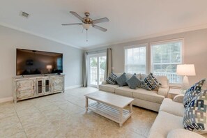 A living room with a television, sofa, coffee table, and ceiling fan.