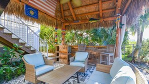 A covered outdoor seating area with wicker furniture, a ceiling fan, and a flag. - Loggerhead Lagoon - Waterfront & Pet Friendly (Sugarloaf Key)