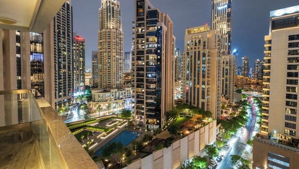 A high-rise residential building complex at night with illuminated windows, a central courtyard, and a pool.