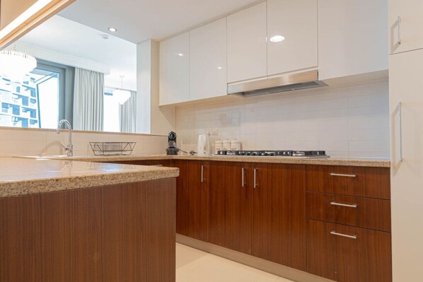 A modern kitchen with wooden cabinets, a stainless steel range hood, and a granite countertop.