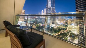 A balcony with a glass railing overlooking a cityscape at night.