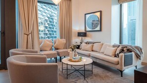 A modern living room with a sofa, two armchairs, a coffee table, and a chandelier.