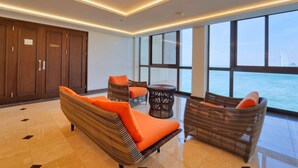 A modern room with a large window, wicker furniture, and a view of the sea.