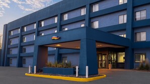 Un hôtel moderne à la façade bleue, doté de plusieurs étages et d’un espace d’entrée abrité.