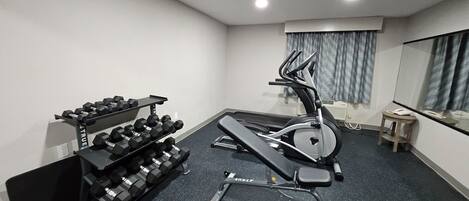 A home gym with a treadmill, dumbbells, and a stationary bike.