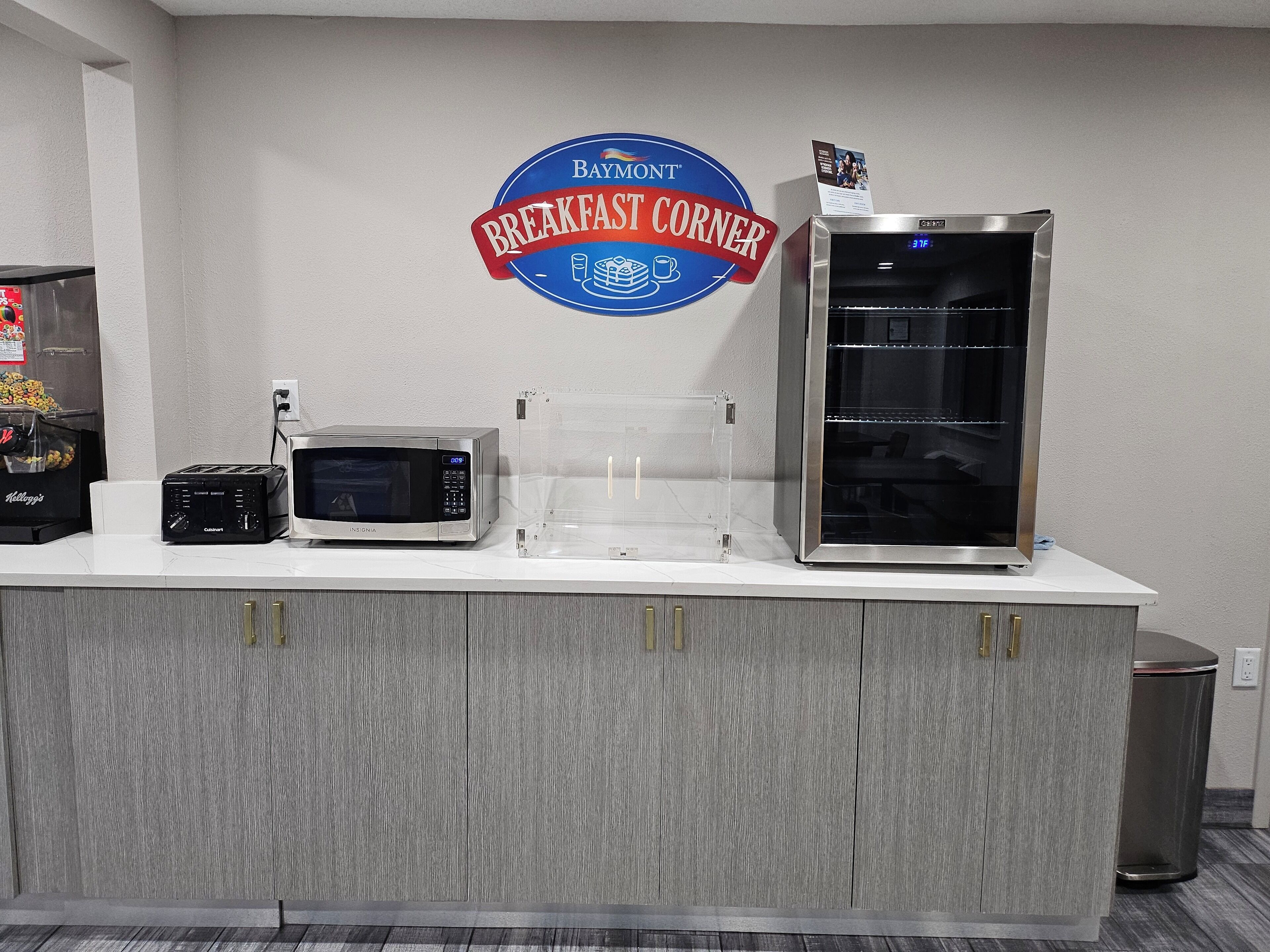 A breakfast station with a microwave, toaster, and refrigerator.