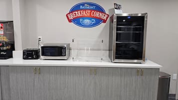 A breakfast station with a microwave, toaster, and refrigerator.