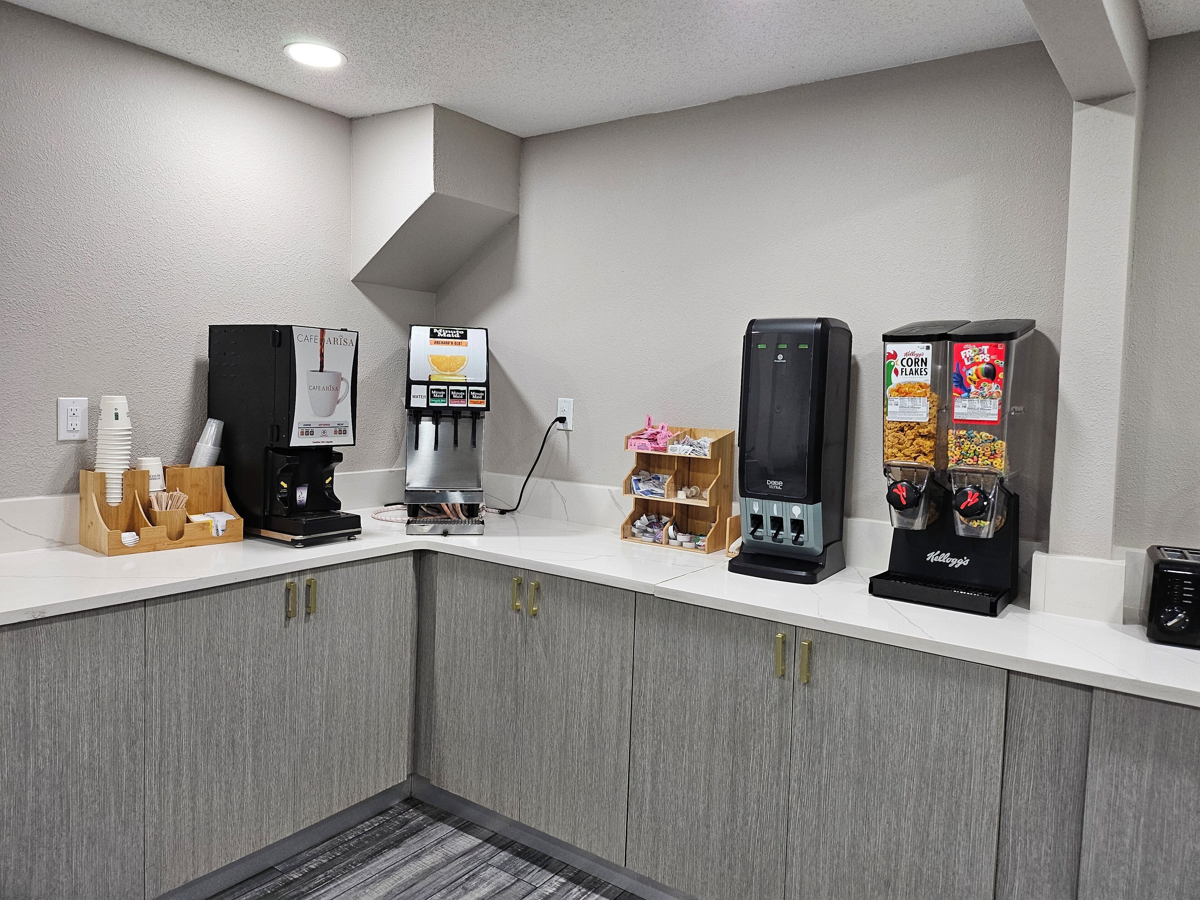 A hotel self-service area with a coffee machine, a water dispenser, and a cereal dispenser.