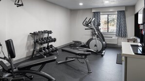 Une salle de sport équipée de machines d’exercice, de supports à haltères et d’un tapis de course.
