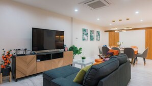 A modern living room with a sofa, TV, and dining area.
