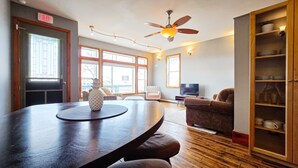 Un vaste espace de vie comprenant une grande table en bois, un ventilateur de plafond et un téléviseur.