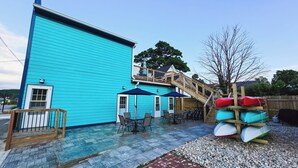 Un bâtiment turquoise doté d’une terrasse et d’un escalier menant à une plateforme.