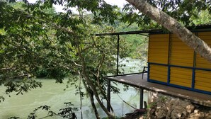 A wooden deck overlooking a river with dense foliage. - Room in Cabin - Rafting Hut by The River (San Agustin Lanquin)