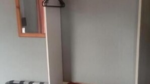 Un armario blanco con una barra para colgar y una toalla enrollada en su interior.