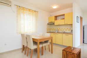 A compact kitchen with yellow cabinets, a wooden dining table, and a small side table.