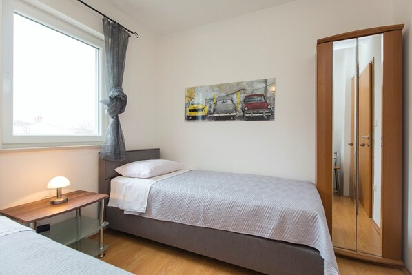 A bedroom with a bed, a bedside table with a lamp, a wardrobe, and a painting on the wall.