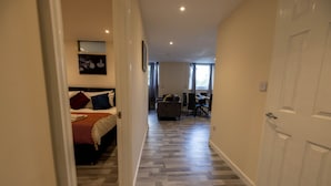 Una habitación de hotel con una cama, un área de comedor y un pasillo.