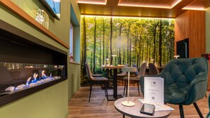 A modern interior with a fireplace, a welcome book, and a view of a forest through a large window. - Villa dei Larici (Spezzano della Sila)