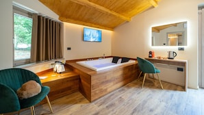 A modern bathroom with a wooden vanity, a large bathtub, and two chairs. - Villa dei Larici (Spezzano della Sila)