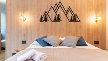 Une chambre d’hôtel avec une tête de lit en bois, un lit recouvert d’une courtepointe matelassée et deux appliques murales.